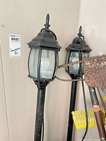 Pair of black metal and glass outdoor post lanterns standing upright