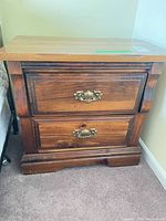 Front view of nightstand showing two drawers, brass pulls, plinth base