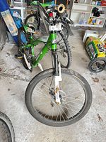 Full view of green and white 24-inch mountain bike in garage