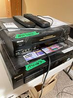 Top and front views of Sears VCR stacked on Sony 5-disc changer with two remotes