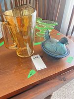 Amber glass pitcher and blue iridescent hen dish on table