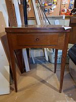 Angled view of closed wood sewing machine cabinet