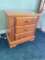 Front view of solid pine nightstand showing three drawers and honey finish
