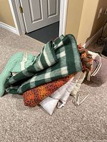 Pile of assorted blankets, seat cushions and bolster pillow