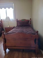 Twin wood bed front view with footboard and bedding