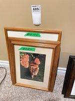 Two wood-framed prints stacked against wall, size labels visible