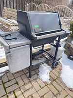 Full view of Weber grill with propane tank attached, side shelf visible