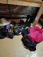Overview of all items on floor: jacket, pants, skates, boots, snorkel gear, bottle, flashlight, gloves