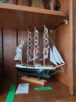 Full view of model ship on shelf showing hull, sails, and stand