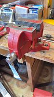 Red cast iron swivel bench vise on workbench