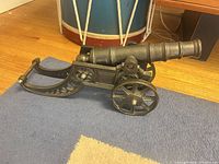 Side view of cast iron cannon on blue rug