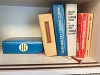 Shelf with three English-Czech technical dictionaries, Roget’s Pocket Thesaurus and additional volumes
