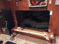 Front view of Insignia 50-inch LED TV on stand with remote visible