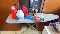 Entire lot on ironing board: ironing board, iron, detergents, bleach, dryer sheets, blue container