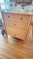 Full view of light wood dresser with four drawers