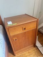 Front and side view of teak veneer nightstand beside bed