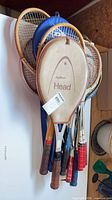 Cluster of wooden racquets with covers showing Head AMF logo and mixed grip colors