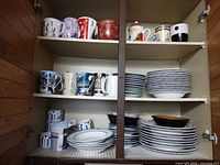 Cabinet with shelves showing mugs, striped plates and bowls, smaller plates