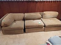 Front view of all three beige/tan modular sofa pieces together.