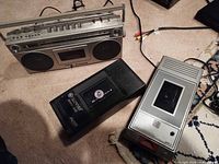 Boombox, Kinyo cassette rewinder, Gemini VHS rewinder and RCA cable on carpet
