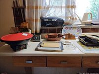 All listed kitchen items arranged on countertop including wok, pans, boombox, bowls, boards, juicer, trays