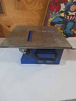 Full view of blue benchmount saw, metal table top