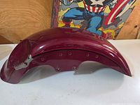 Side view of burgundy Harley-Davidson front fender showing curvature and mounting holes