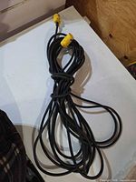 Full view of coiled black extension cord with yellow ends