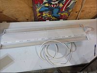 Full view of white LED high bay fixture with power cord on table