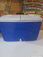 Front view of blue Rubbermaid cooler showing brand logo and drain plug