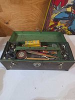 Closed metal toolbox open to show filled green tray and lower compartment of tools