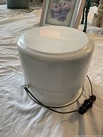 Base of white enameled chamber pot, showing underside and bail handle