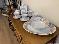 Set displayed on sideboard: cups, saucers, platter, bowls, lidded sugar bowl visible