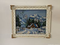Winter cottage needlepoint artwork in ornate white/gold frame