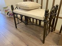 Full view of metal bench with cushion and pillow