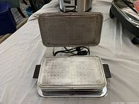 Panini press open showing cooking plates and power cord