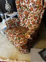 Front angled view showing floral upholstery, padded arms, skirted base