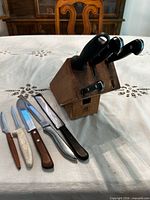 Overall view showing wooden block with four knives inserted and five knives laid out