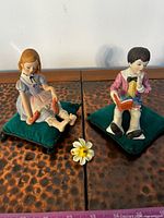 Both figurines on cushions with loose flower shown