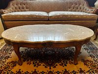 Oval coffee table showing marble top, carved wood base and drawer hardware