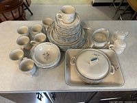 Full set on countertop showing stacks of plates, bowls, mugs, casserole, baking dish, creamer and sugar bowl