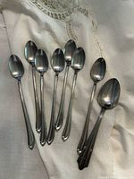 Eight teaspoons arranged on fabric showing full shape and condition