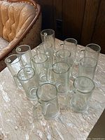 13 clear glass handled beer mugs grouped on marble-look surface