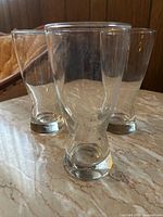 Three clear glass pilsner glasses front view