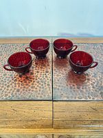 Four ruby red glass teacups on tabletop