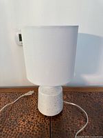 Front view of table lamp showing shade, ceramic base and cord