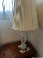 Front view showing crystal body, brass base, pleated fabric shade