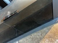 Top view of black TV stand with remote placed for scale