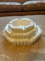 Stacked view of three white hobnail milk glass ashtrays