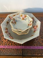 Top view of serving bowl with five small bowls stacked inside, showing floral design and octagonal shape